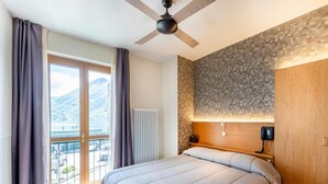 Une chambre à coucher avec un lit, un ventilateur de plafond, une vue sur les montagnes et une tête de lit en bois.