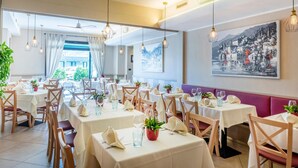 Un restaurant doté de nombreuses tables, aménagé pour accueillir les clients, et offrant une vue sur l’extérieur grâce à de grandes fenêtres.