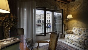 A room with a large window, a sofa, a chair, a table, and a lamp. - Hotel Al Ponte Antico (Venice)