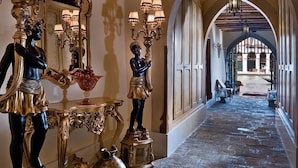 An ornate hallway with classical architecture, featuring a grand chandelier, statues, and a reflective floor. - Hotel Al Ponte Antico (Venice)