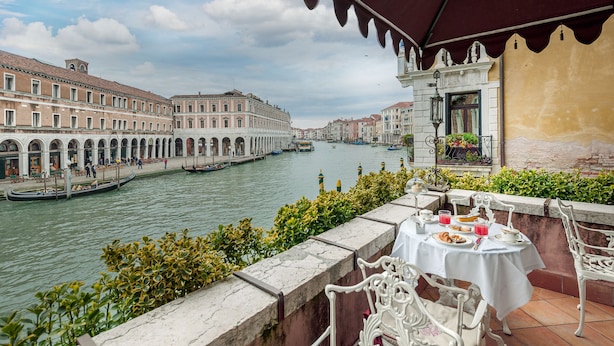 A terrace with a table set for dining, overlooking a canal with buildings and gondolas. - Hotel Al Ponte Antico (Venice)
