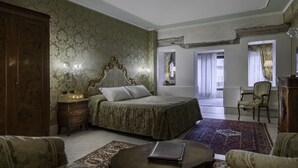 A bedroom with a large bed, a nightstand, a dresser, and a chair. There is a window with curtains and a view of the outside. - Hotel Al Ponte Antico (Venice)