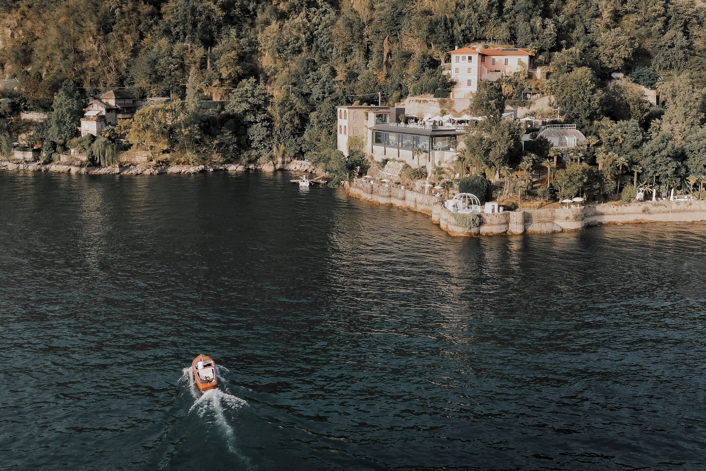 Um barco num lago, com casas numa encosta ao fundo.