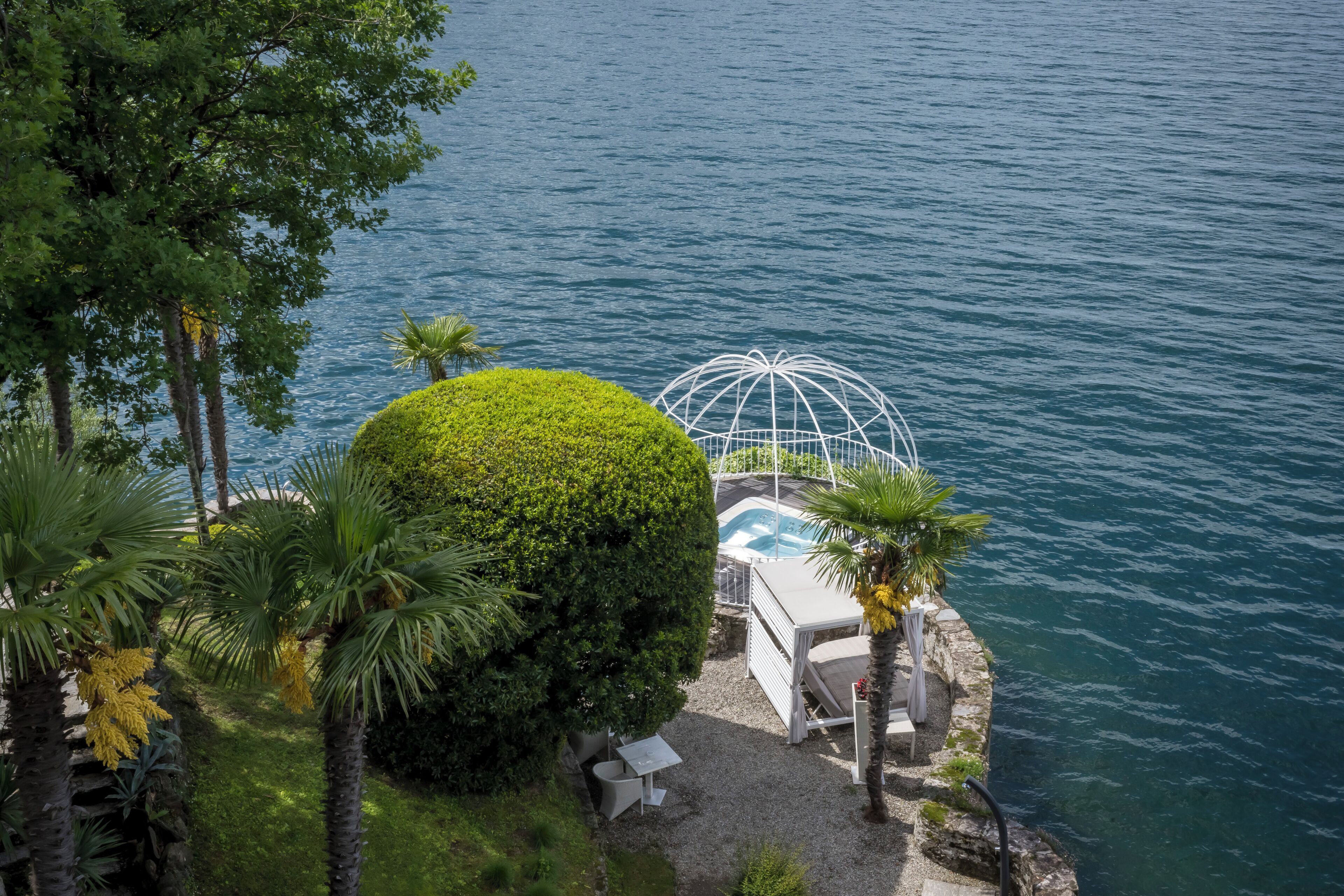 Un área de piscina privada con una estructura en forma de cúpula, rodeada de exuberante follaje y palmeras.