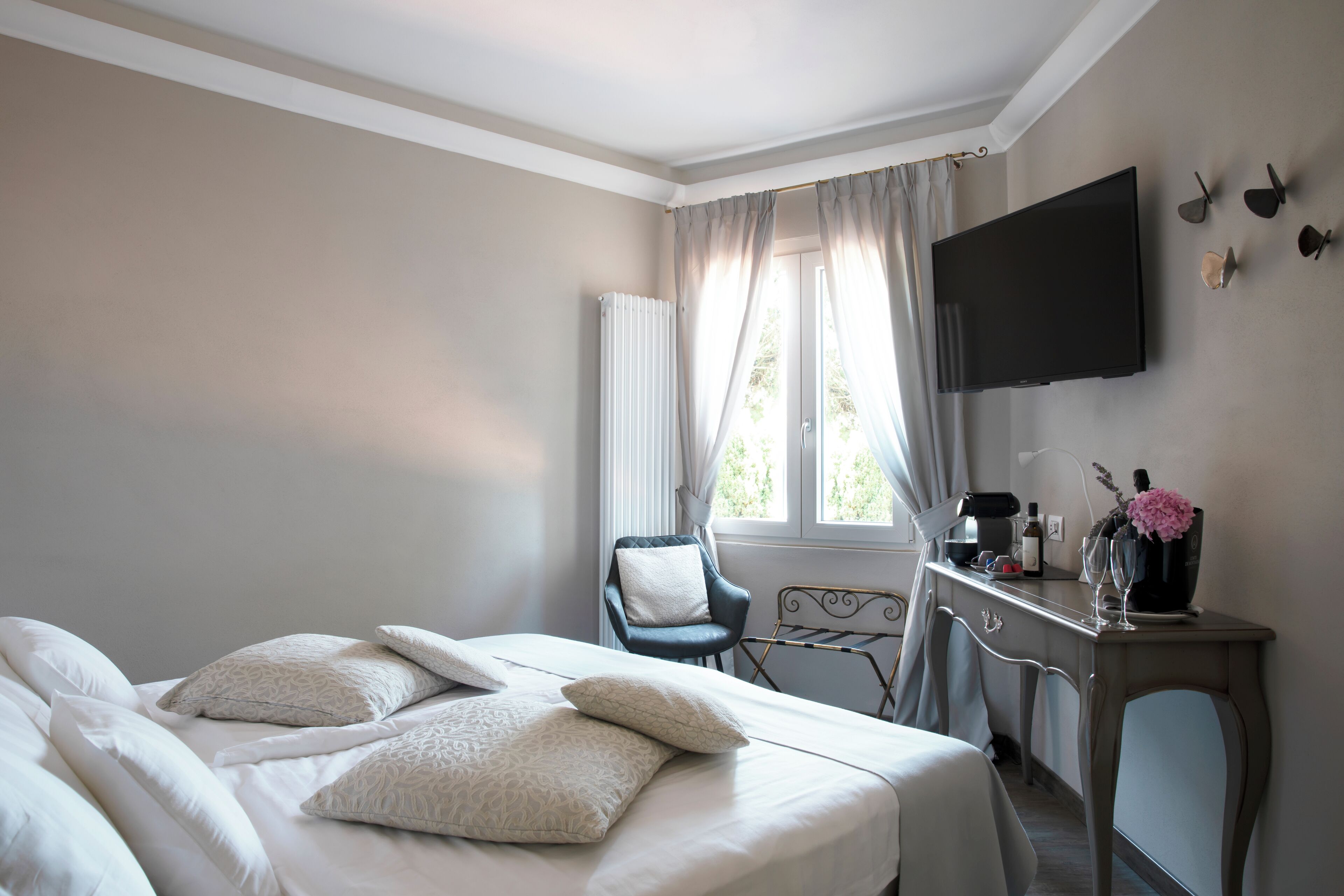 A hotel room with a bed, a desk, a chair, a TV, and a window with curtains.