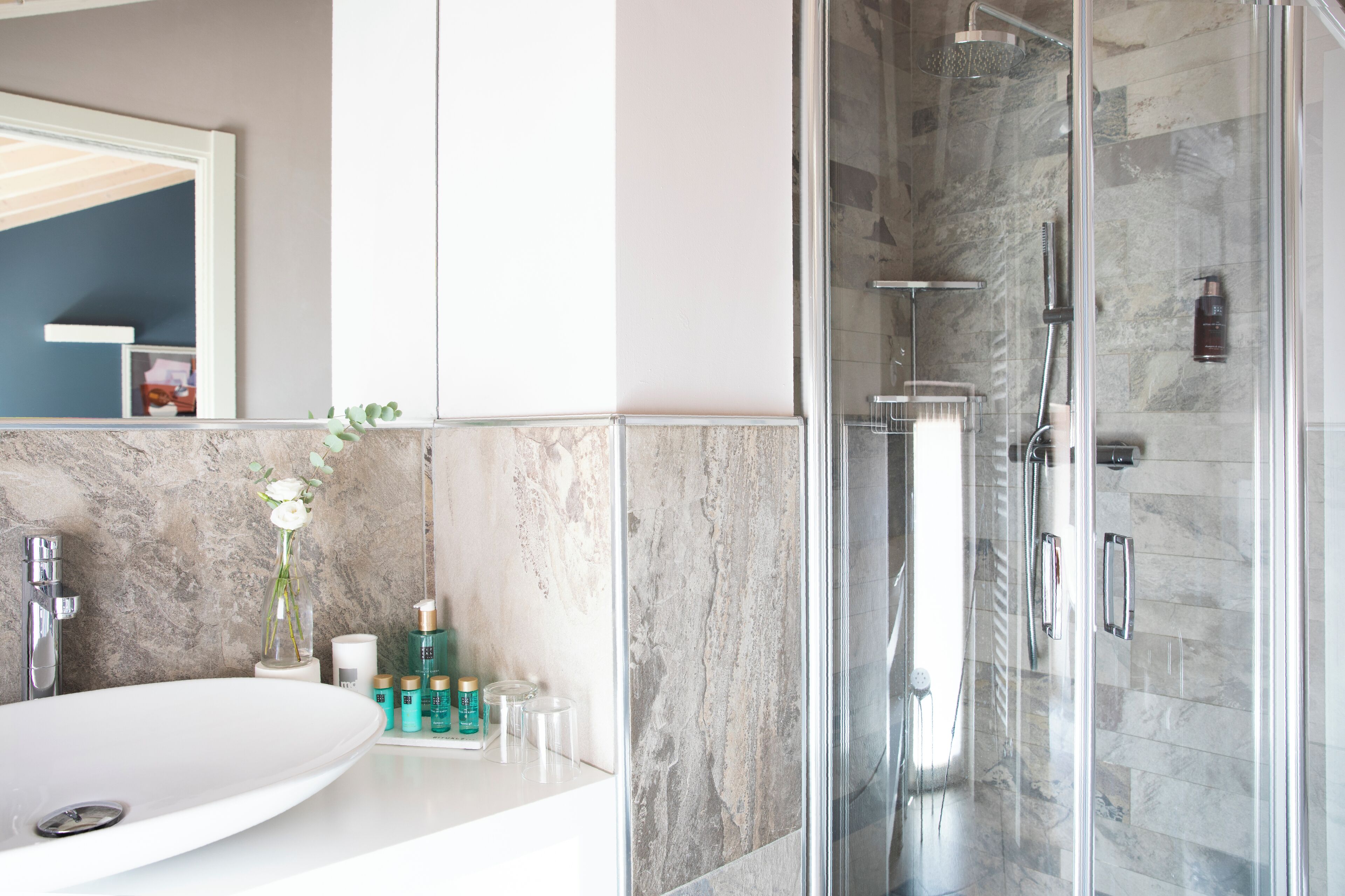 Une salle de bain moderne avec un grand lavabo blanc, une douche en verre et des carreaux de marbre.