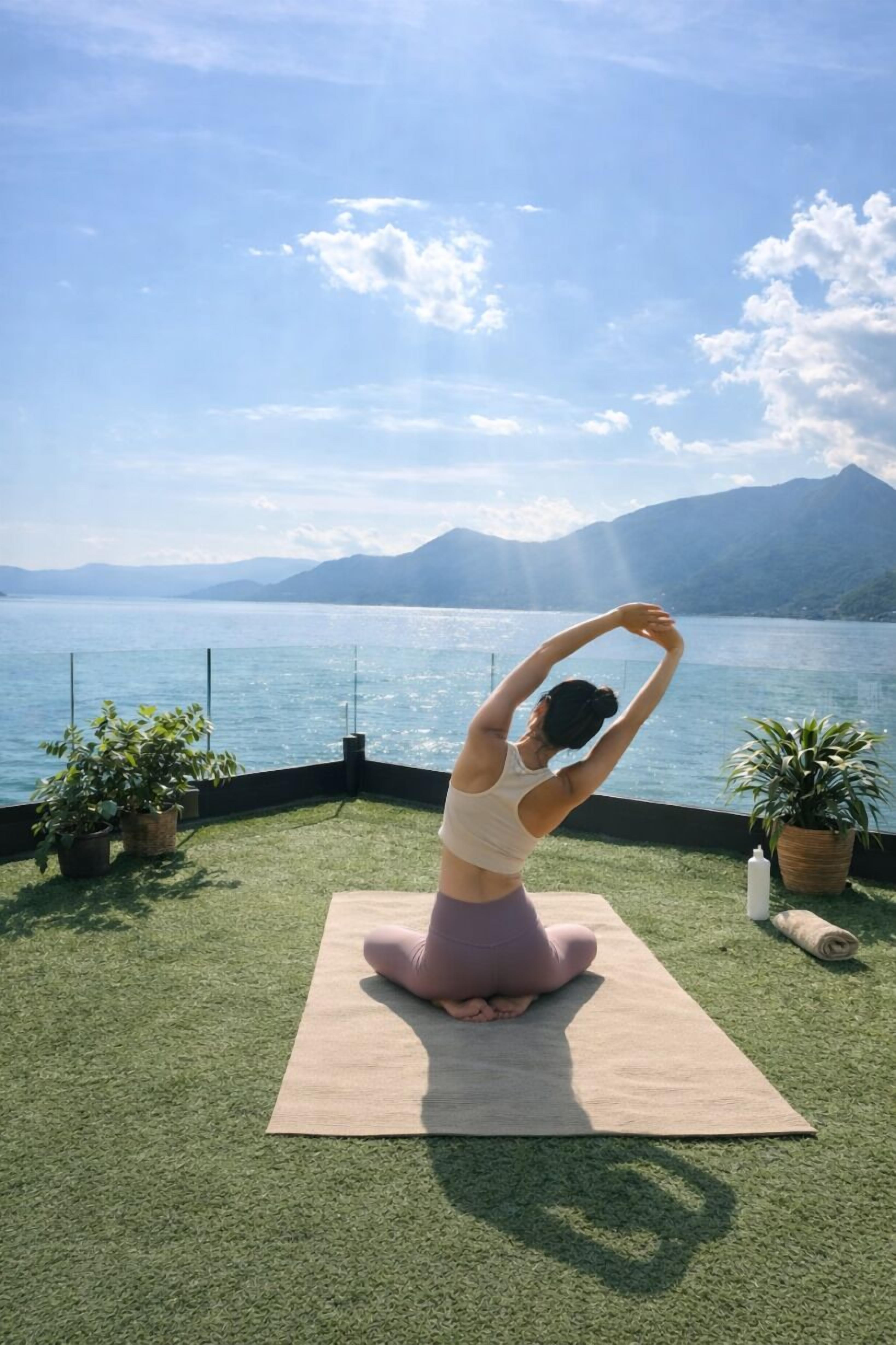 Une personne pratiquant le yoga sur un tapis, avec une vue pittoresque sur un lac.