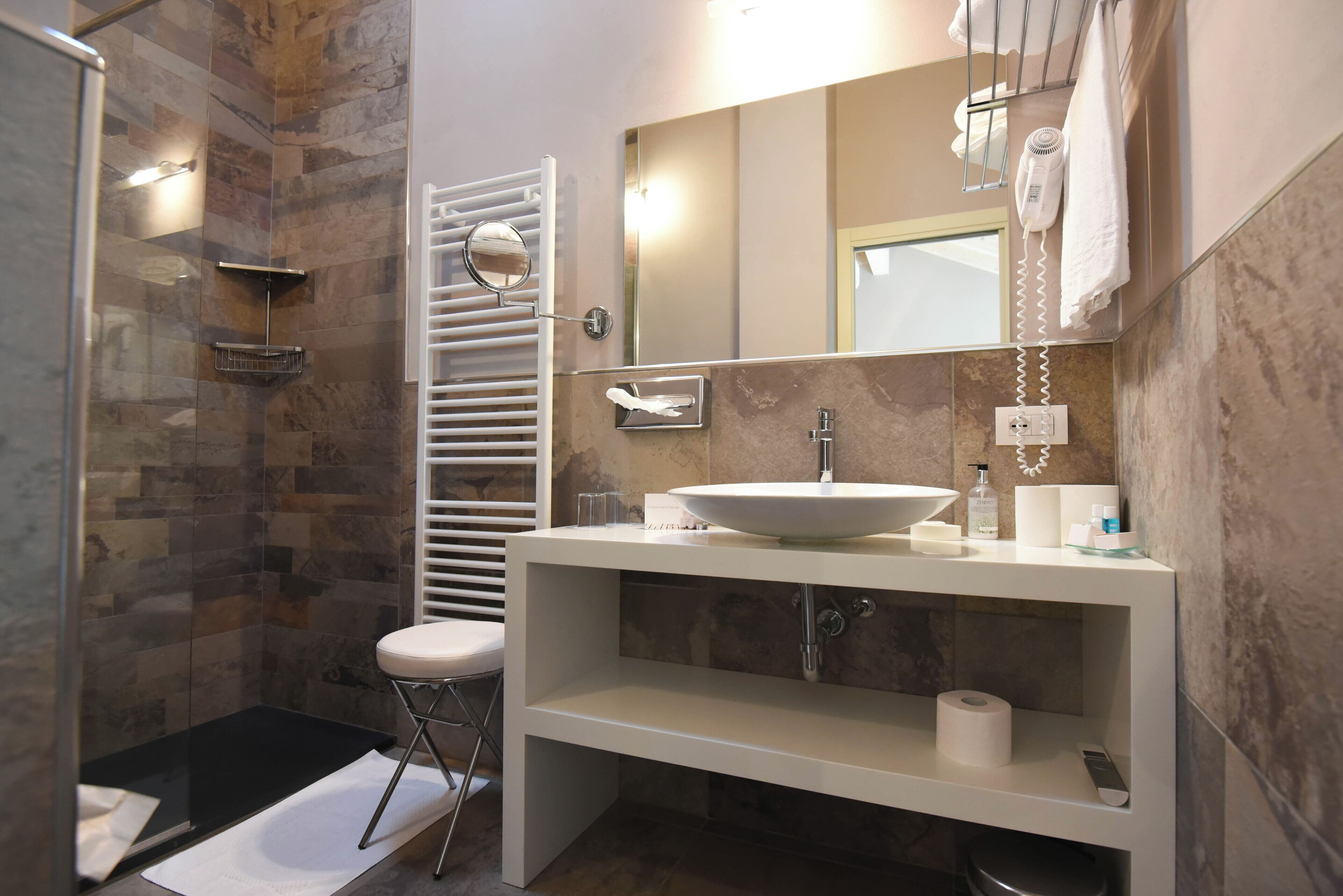 Un bany modern amb plat de dutxa de vidre, un lavabo blanc i un mirall gran.