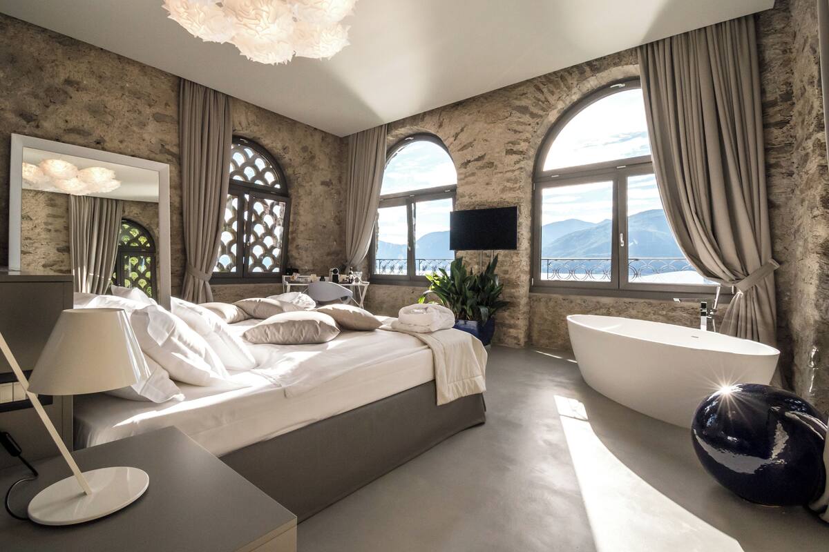 Ein modernes Schlafzimmer mit einem großen Bett, einer Badewanne und einem Fernseher.