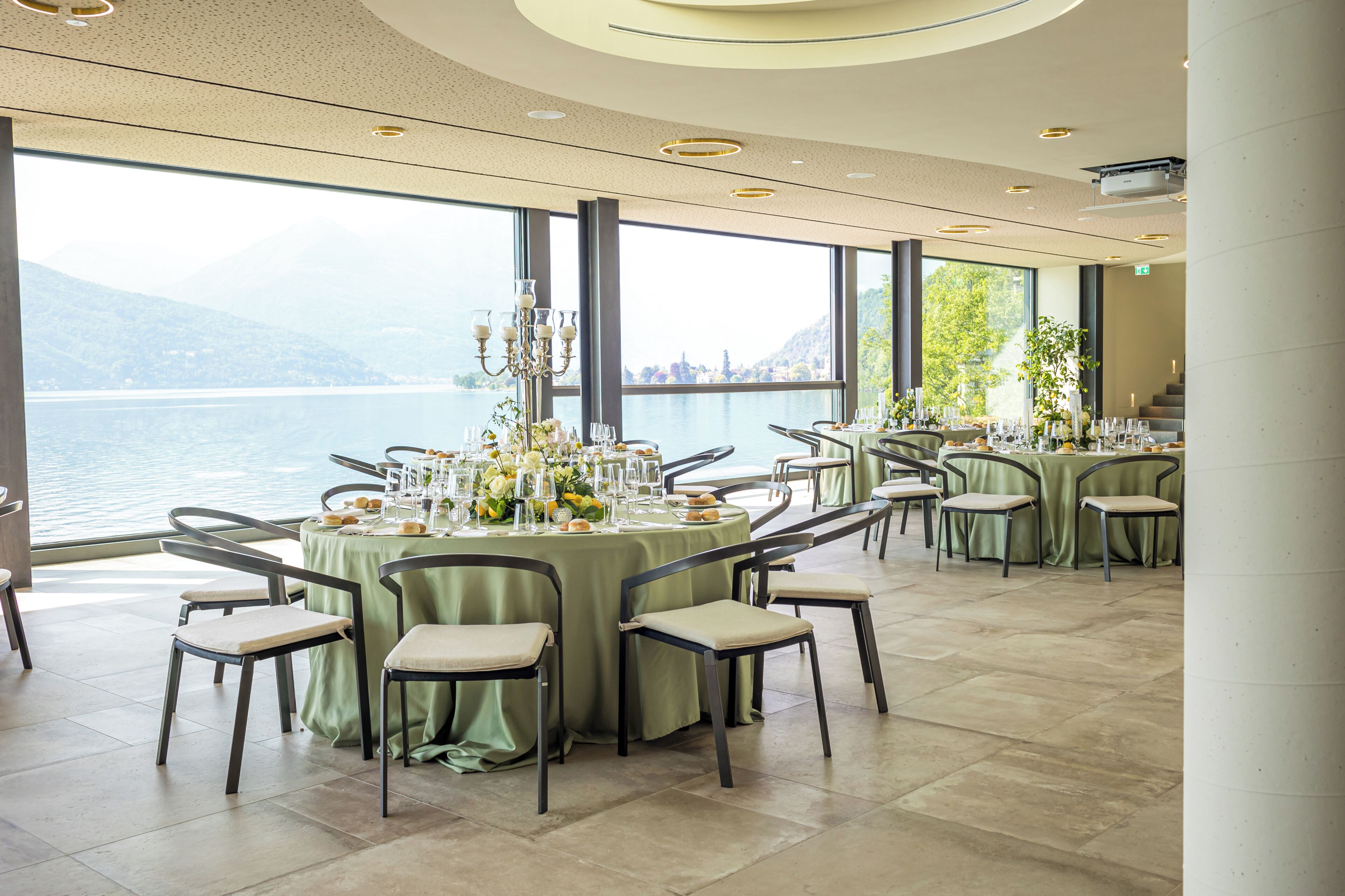 Ein Restaurant mit runden Tischen, Stühlen und Blick auf einen See.