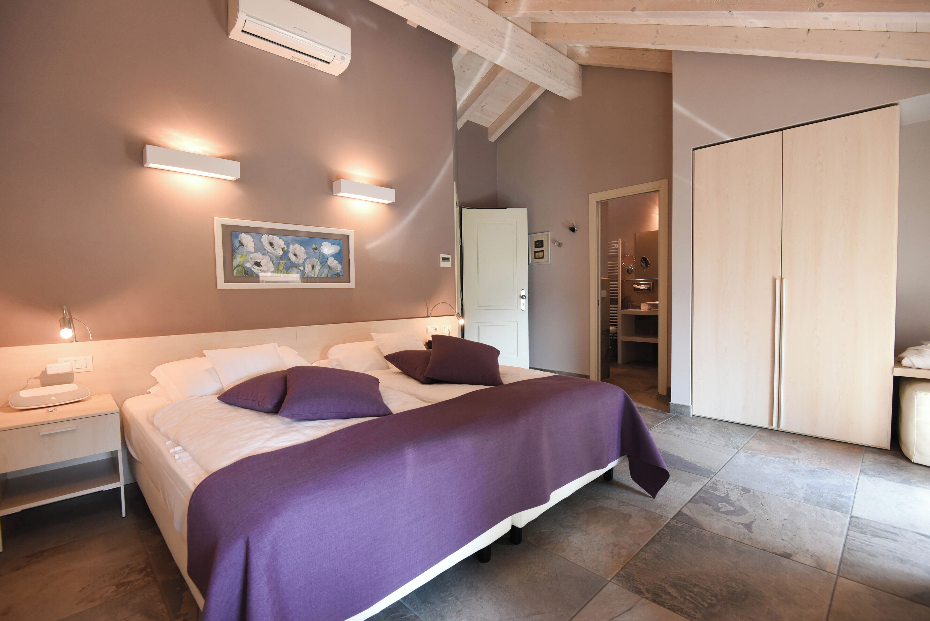 Ein Schlafzimmer mit einem großen Bett, einem Nachttisch, einem Wandbild und einem Kleiderschrank.