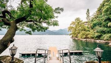 A wooden dock leading into a lake, surrounded by trees and mountains in the background.