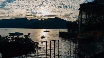 A waterfront view with boats, mountains, and a building with a balcony.