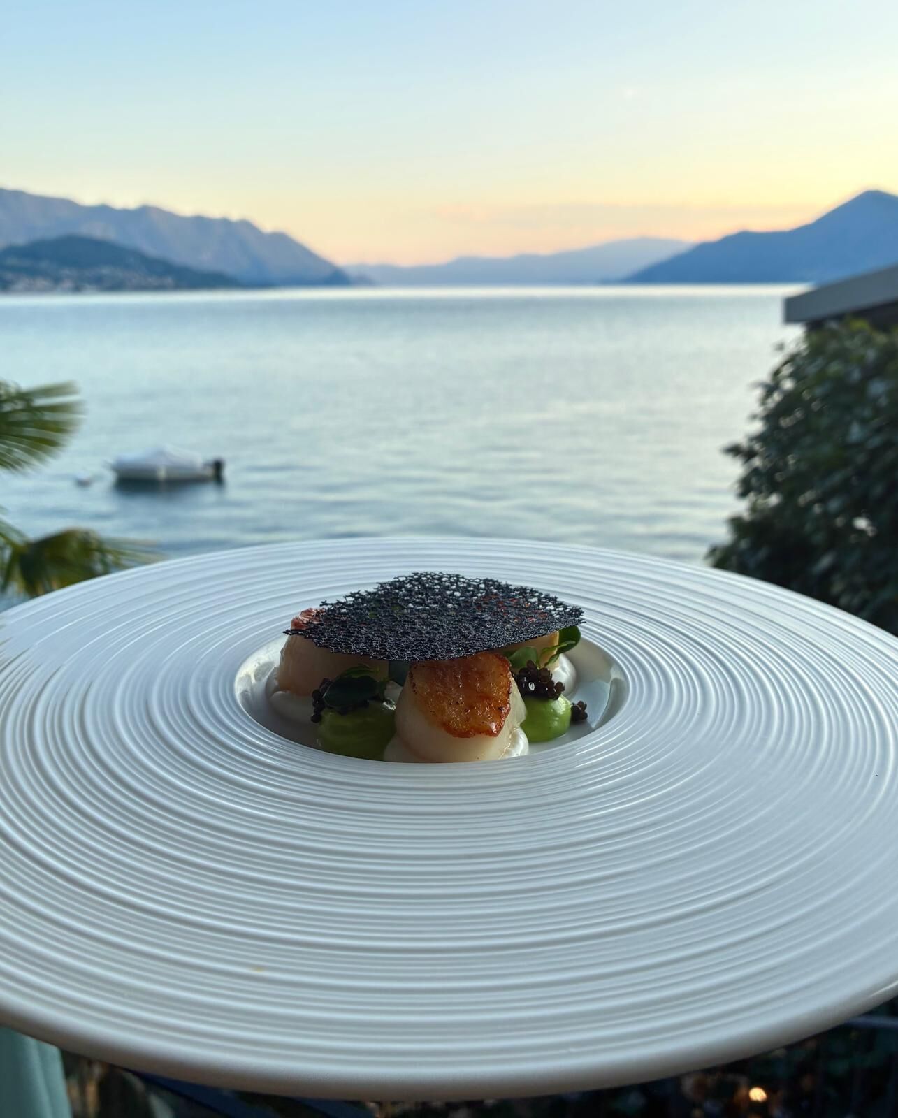 Une assiette remplie de nourriture, avec en toile de fond une étendue d’eau calme et des montagnes.
