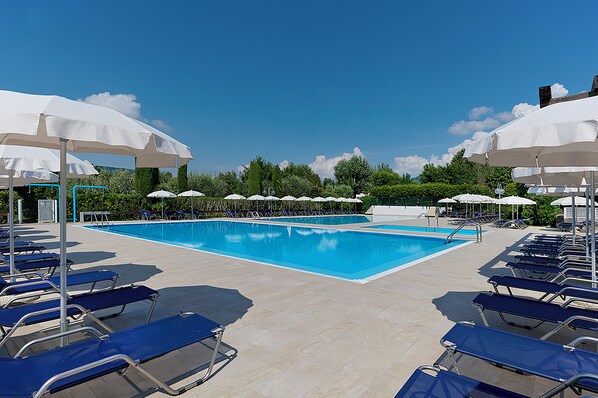 Relax by the spacious pool surrounded by lush greenery and lounge chairs.
