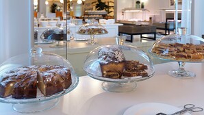 Un buffet proposant divers desserts présentés sous des cloches en verre, une table blanche et, en arrière-plan, le reflet de la pièce.