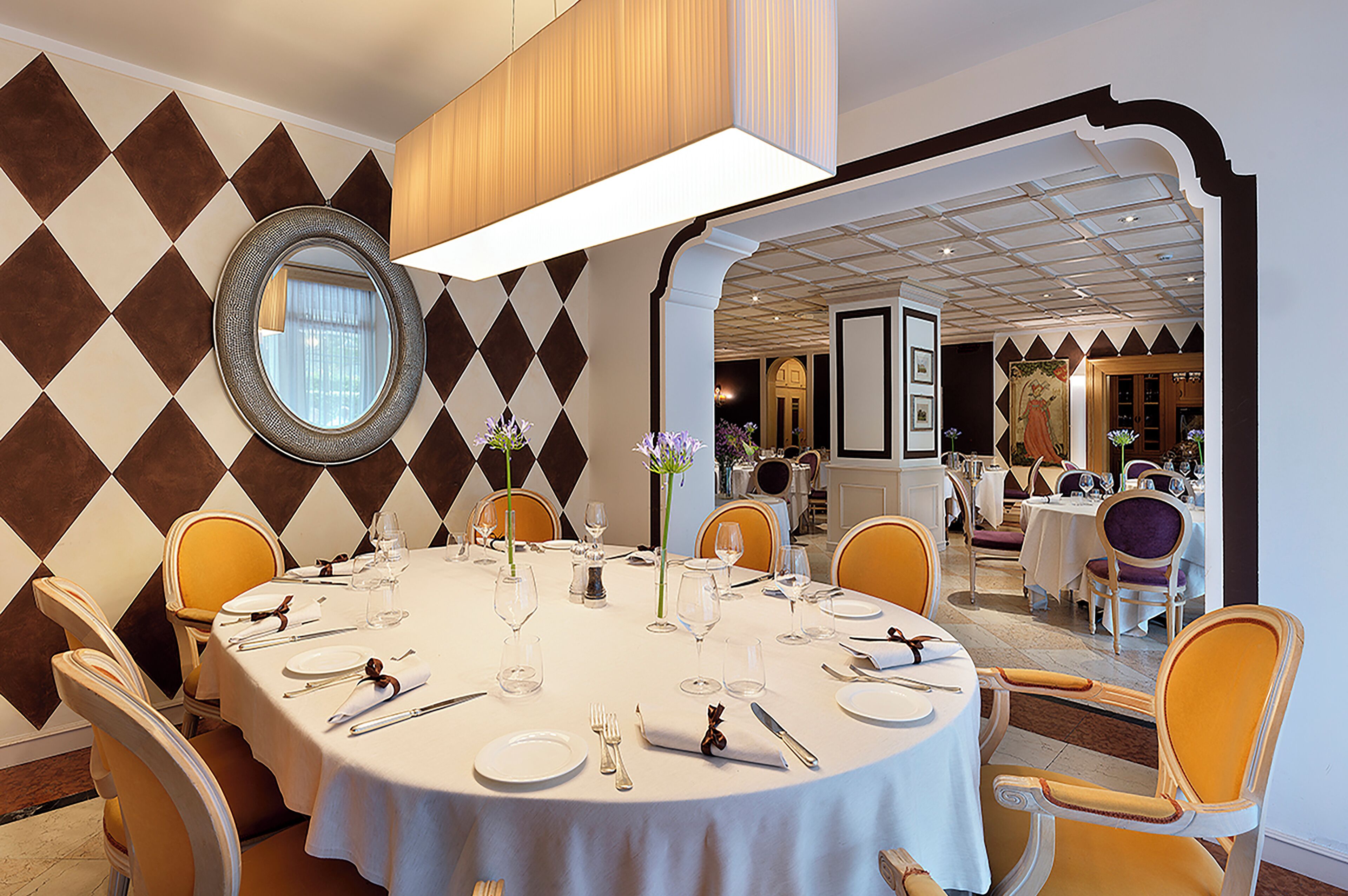 A dining area with a round table set for a meal, surrounded by yellow chairs.
