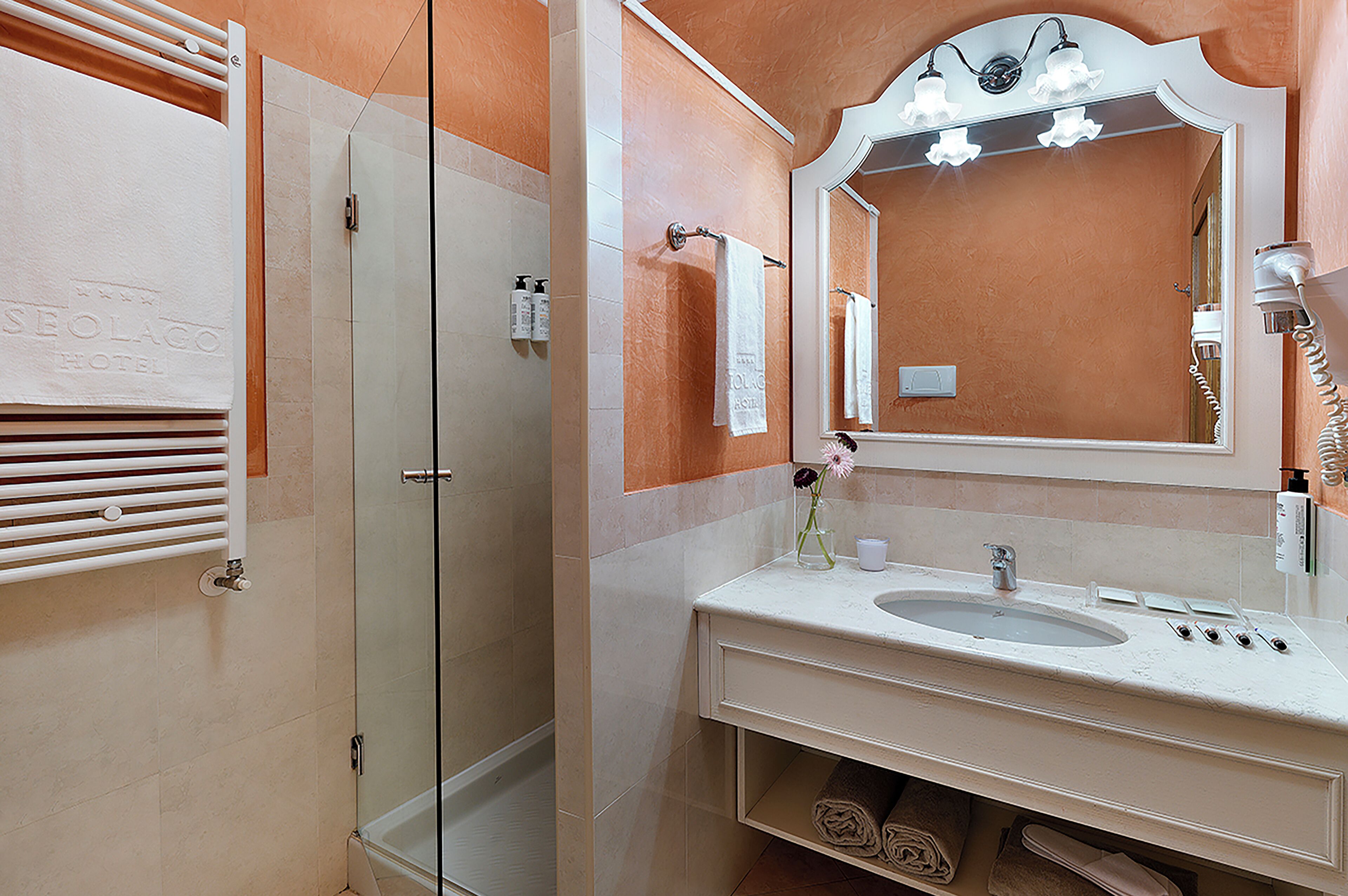 A bathroom with a glass shower enclosure, a sink with a mirror, and a towel rack.