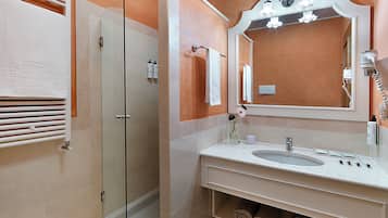 A bathroom with a glass shower enclosure, a sink with a mirror, and a towel rack.