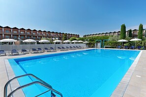 Relax by the rectangular pool surrounded by comfortable lounge chairs and umbrellas.