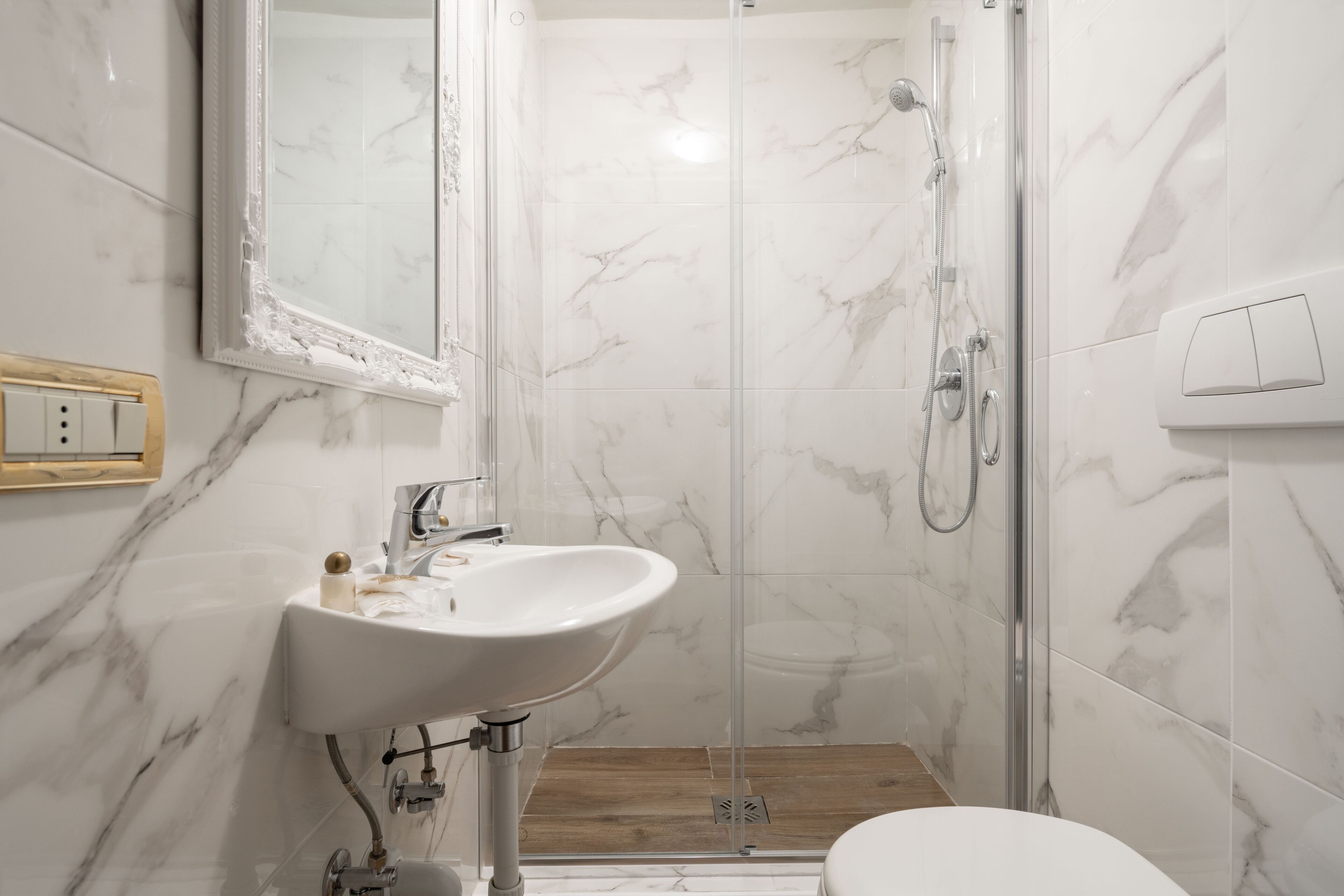 Une salle de bain avec un lavabo en marbre, une cabine de douche en verre et des toilettes.