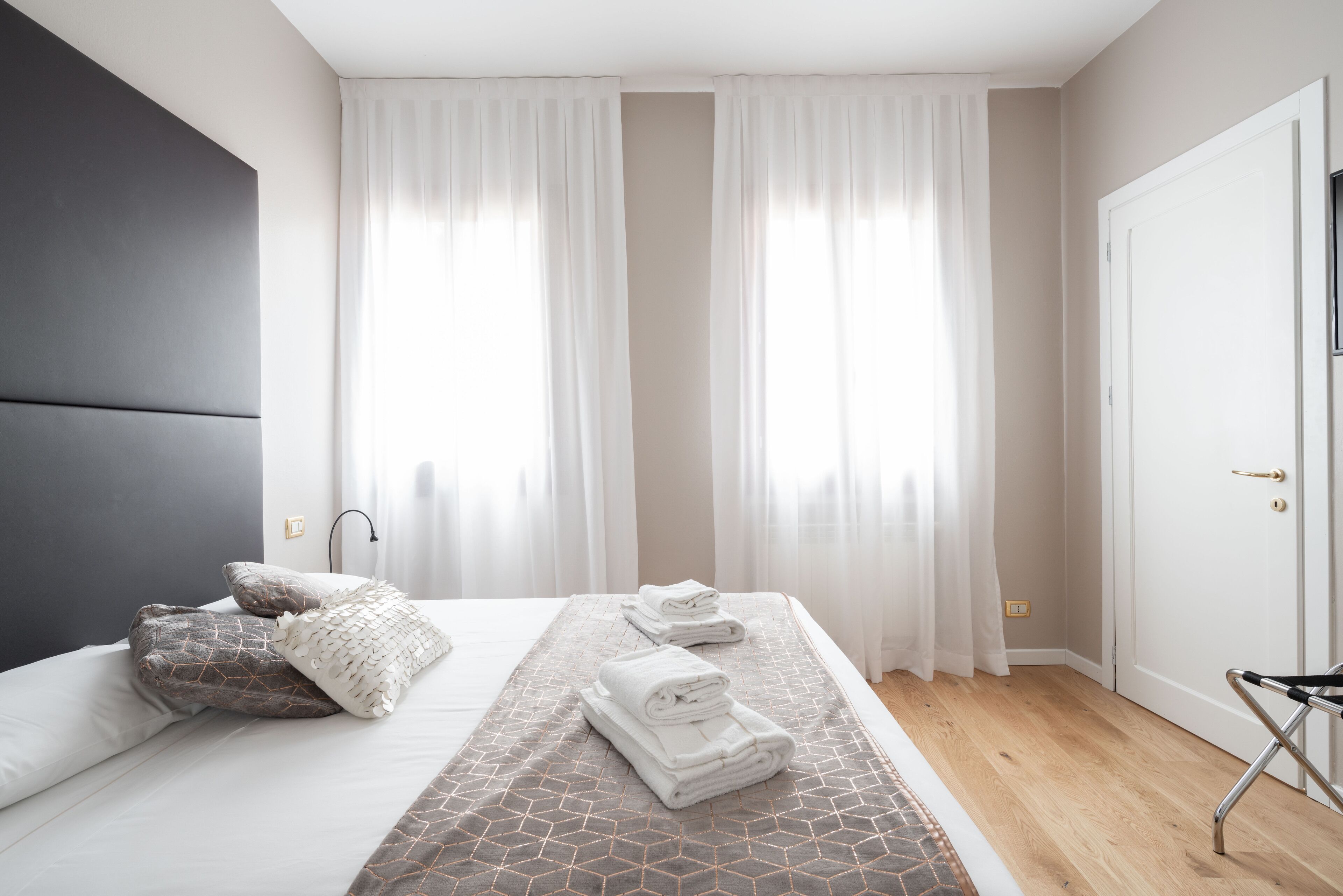 A modern hotel room with a bed, a bedside table, and a chair.
