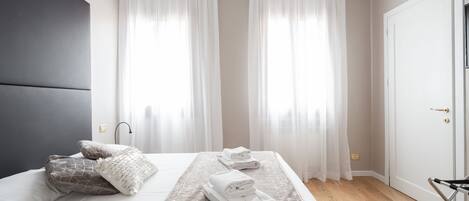 A modern hotel room with a bed, a bedside table, and a chair.