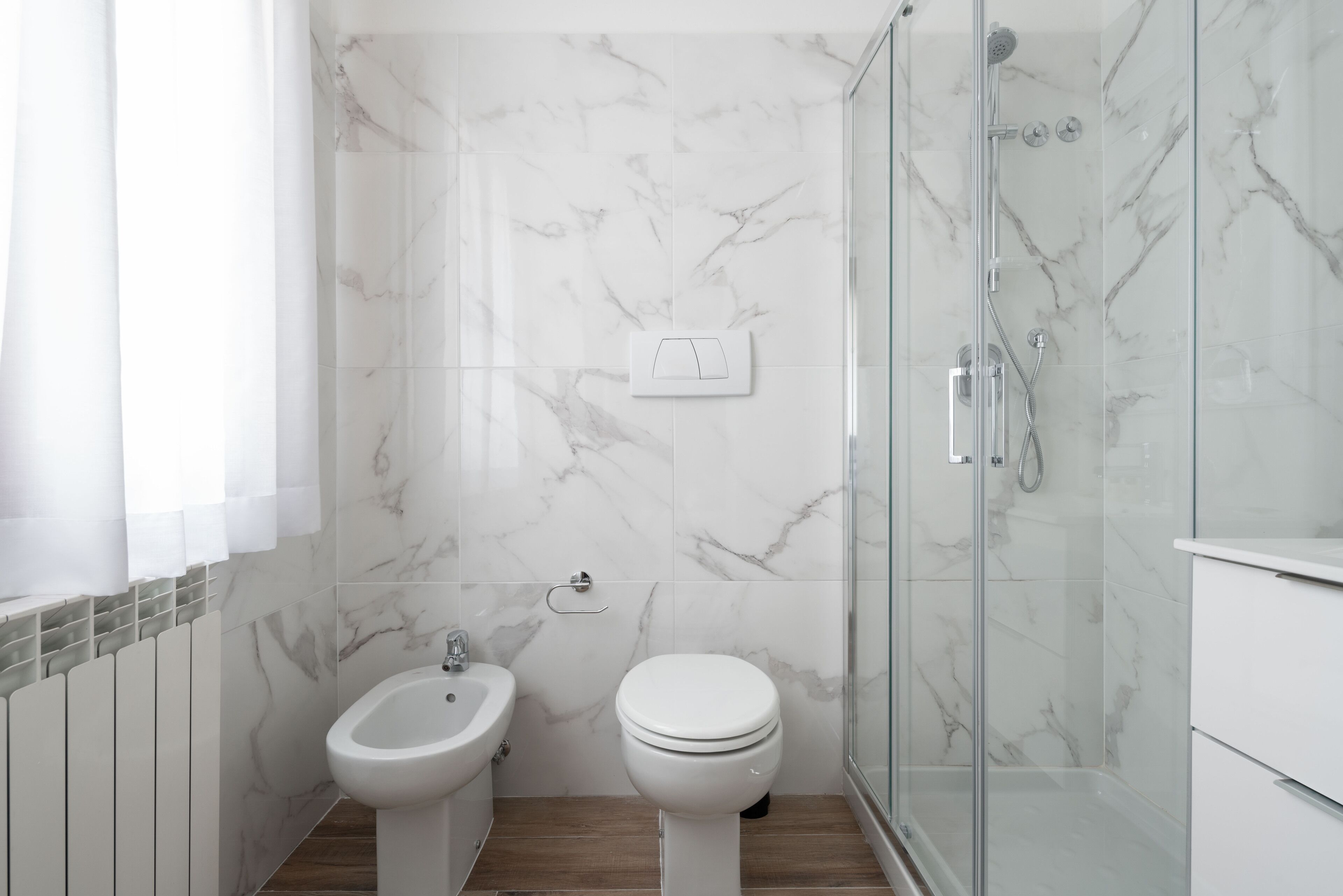 A modern bathroom with a bidet, toilet, and glass-enclosed shower.
