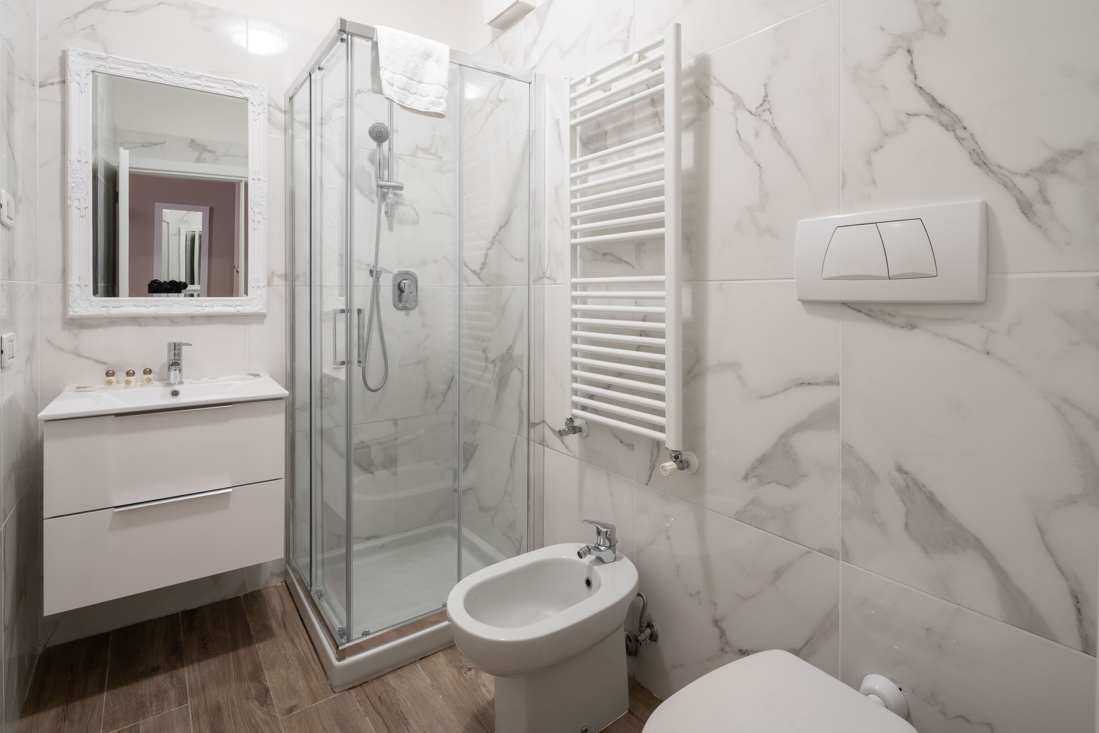 Un baño moderno con ducha de vidrio, un bidé, un inodoro y un lavamanos con espejo.
