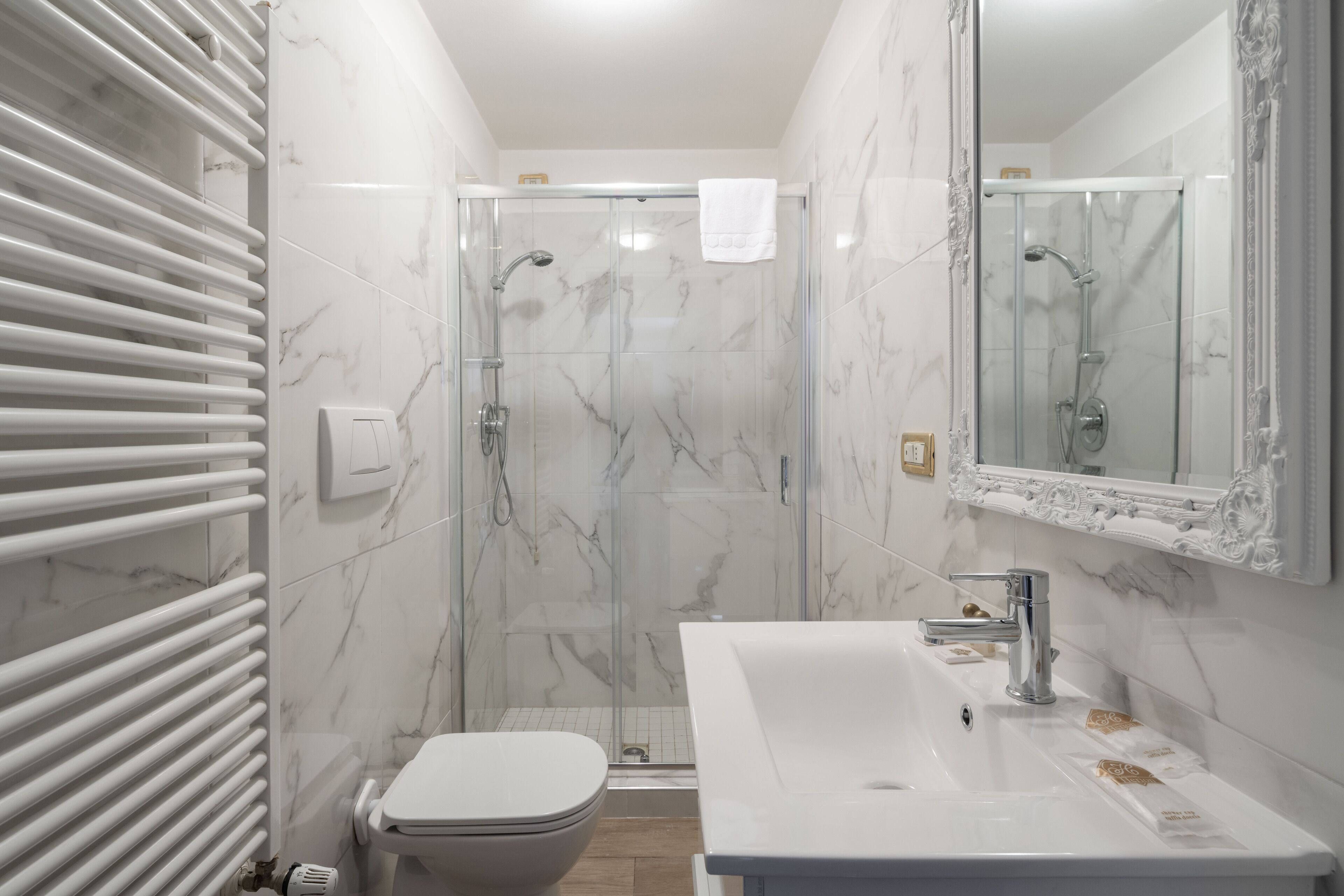 A bathroom with a glass-enclosed shower, a white sink, and a toilet.