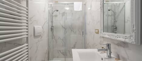 A bathroom with a glass-enclosed shower, a white sink, and a toilet.