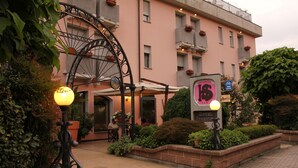 En rosa byggnad med en stor, utsmyckad järngrind, en skylt som visar att det är ett hotell, och en cykel parkerad framför.