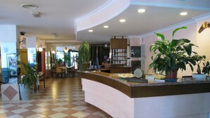En hotellobby med en incheckningsdisk, en receptionsdisk, en matplats och en bar.