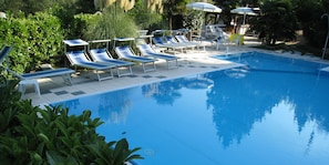 A swimming pool with lounge chairs and umbrellas, surrounded by greenery. - Albergo Boomerang (Salsomaggiore Terme)