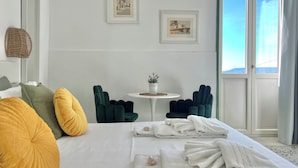 A hotel room with a bed, two chairs, a small table with a plant, and two framed pictures on the wall. - Hotel Posta (Syracuse)