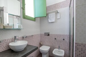 A bathroom with a white sink, a white toilet, and a bidet. There is a mirror above the sink and a green cabinet.