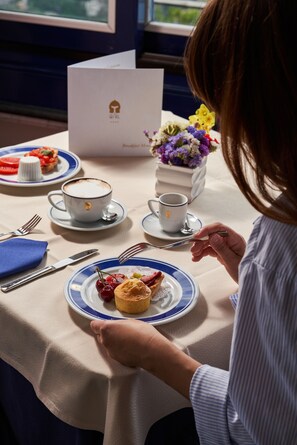 Desayuno con una mesa, platos, tazas y una caja.