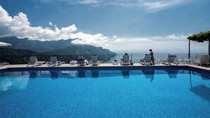 A swimming pool with lounge chairs and a view of mountains. - Hotel Graal (Ravello)