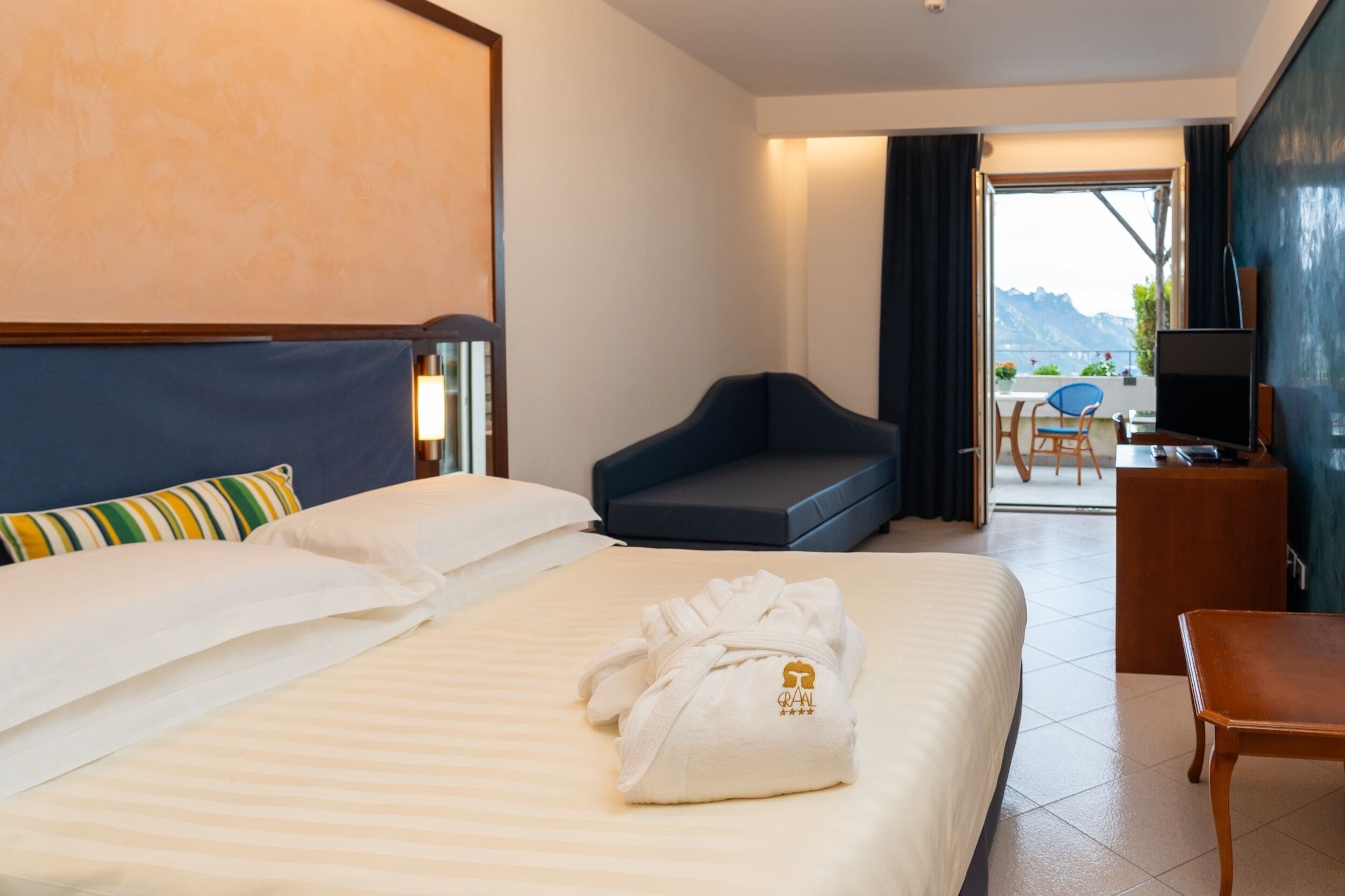 Une chambre d’hôtel avec un lit, un canapé, une télévision et un bureau.