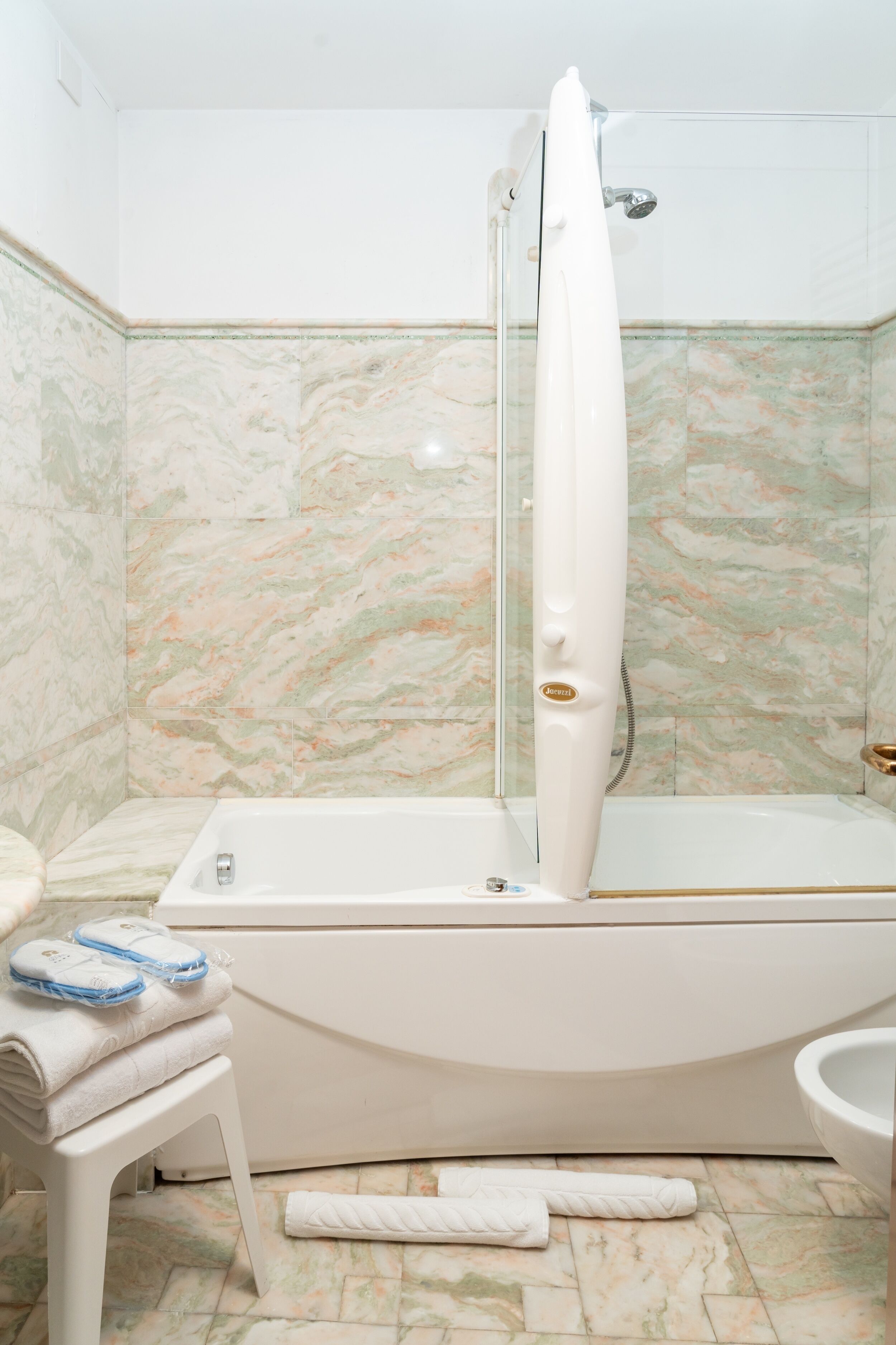 Un bagno con vasca, doccia e servizi igienici. Sul pavimento, asciugamani e un tappeto.