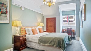A bedroom with a bed, nightstands, a dresser, a window, and a door.