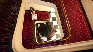 A reflection in a mirror on a red carpeted staircase with a checkered floor.