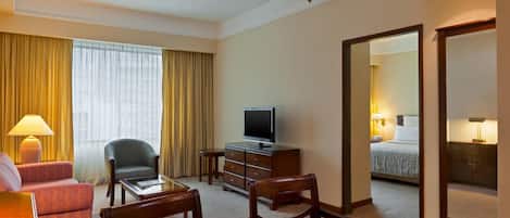 Quarto de hotel com televisão, escrivaninha, cadeira, sofá e cama.