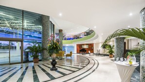 Un moderno vestíbulo de hotel con un diseño de piso curvo, una zona de estar central y un piano.