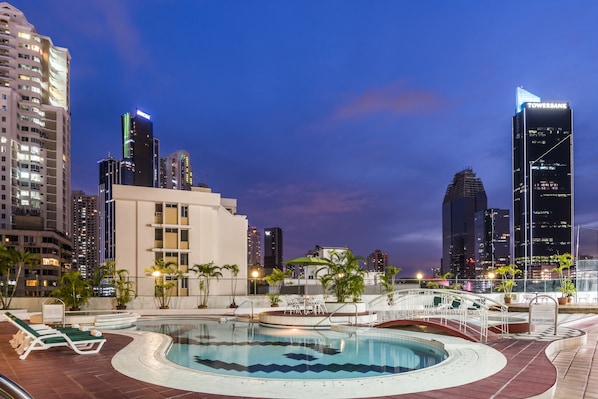 Una piscina al aire libre, sillones reclinables de piscina