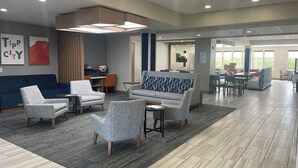 A spacious lobby with a reception desk, seating area with armchairs and sofas, and a dining area with tables and chairs. - Holiday Inn Express Hotels and Suites Dayton North Tipp City by IHG (Tipp City)