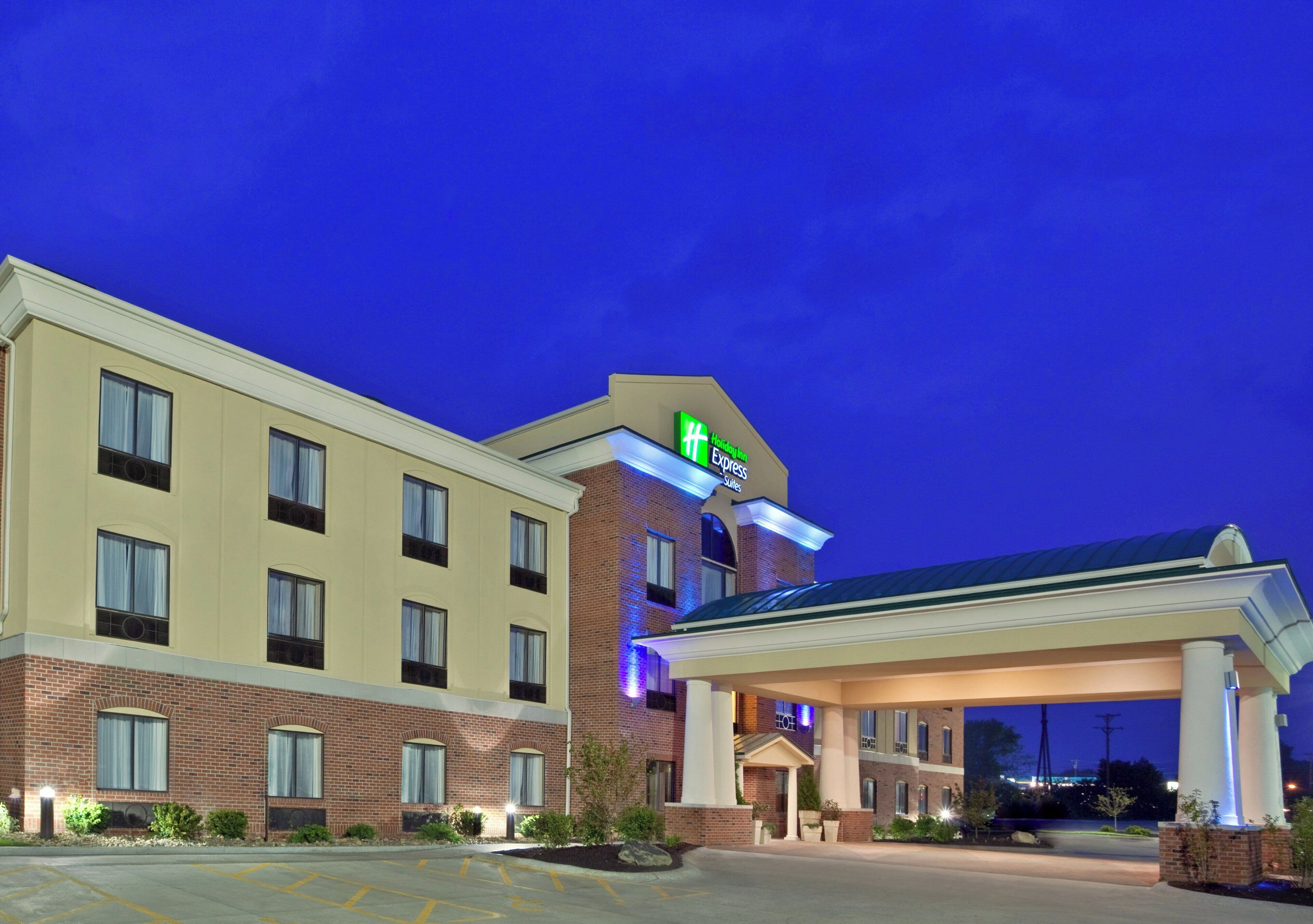 Un hotel Holiday Inn Express con fachada de ladrillo, entrada cubierta y estacionamiento.
