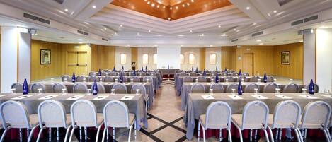 A conference room with multiple tables and chairs, equipped with nameplates and water bottles.
