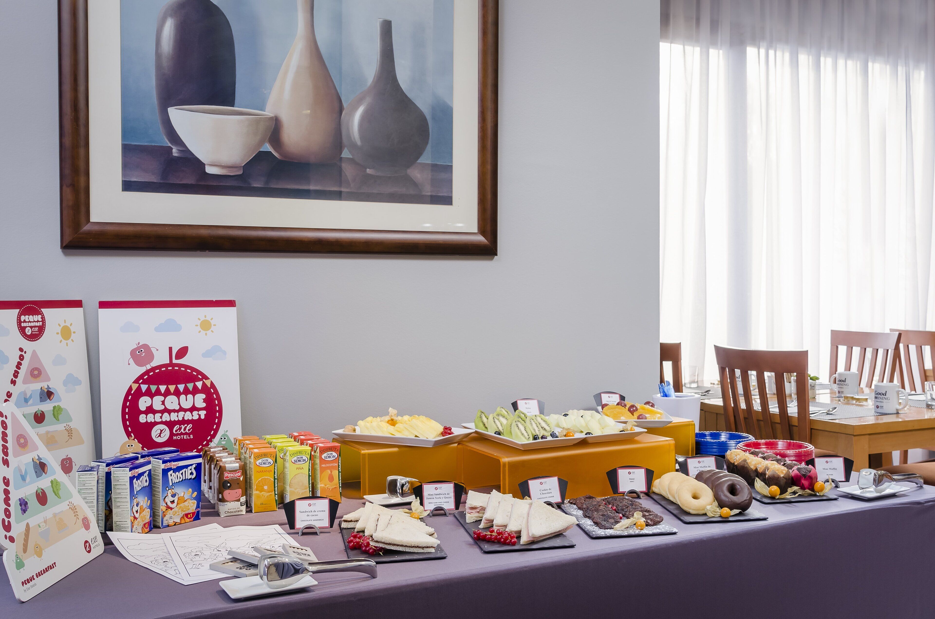 Buffet de l'esmorzar amb diferents aliments i una obra d'art emmarcada a la paret.