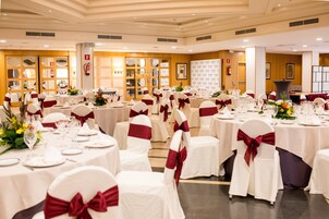 A banquet hall with round tables, white tablecloths, and chairs with red sashes.